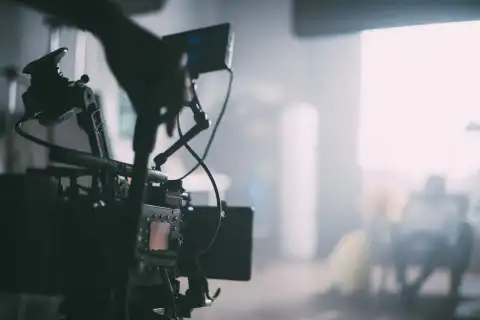 Una cinepresa professionale sul set, con le luci accese dietro