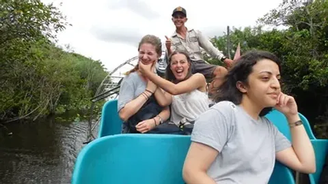 Ragazzi a bordo di un airboat fra le mangrovie, con la guida al timone