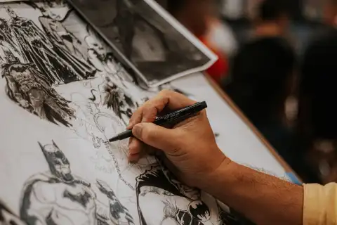 Una mano disegna a china la tavola di un fumetto